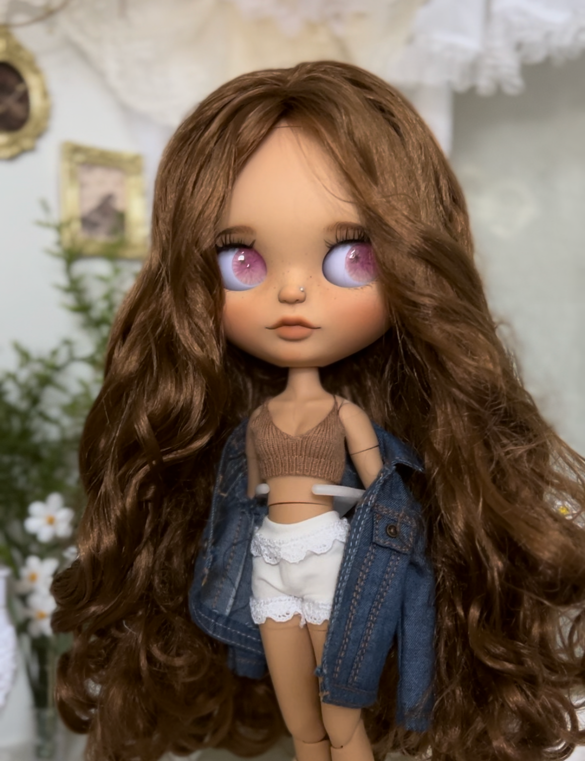 Doll with long brown hair and denim jacket in a decorative setting
